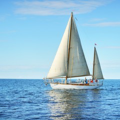 Vintage wooden two mast yacht sailing in a open sea on a clear day