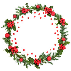 Winter & Christmas juniper fir wreath with red baubles & loose  holly berries on white background with copy space. Traditional symbol for the festive season.