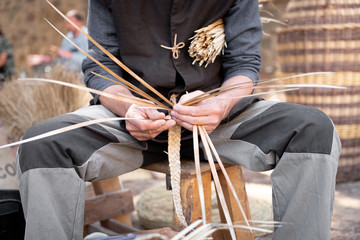 old wicker craftsman with hands working in isolated foreground.