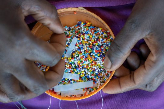 Making of handmade jewellery. Box with beads and african women hands, top view, close up. Island of Zanzibar, Tanzania, Africa