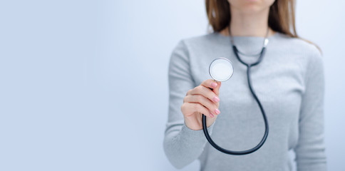 Woman holding stethoscope medicine health care on gray light background, space for text