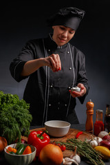Girl cook in a black uniform prepares food.