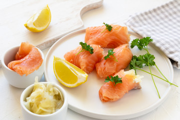 Slices of smoked salmon wrapped with cottage cheese and marinated ginger. Party snack.