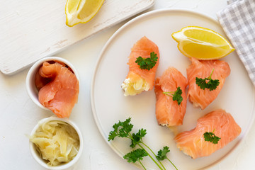 Slices of smoked salmon wrapped with cottage cheese and marinated ginger. Party snack.