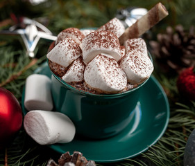 Christmas cappuccino with marshmallows in a green mug, fir branches, Christmas  toys
