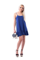 Confident young cute blond woman in summer blue dress posing with trendy handbag. Full body isolated on white background. 
