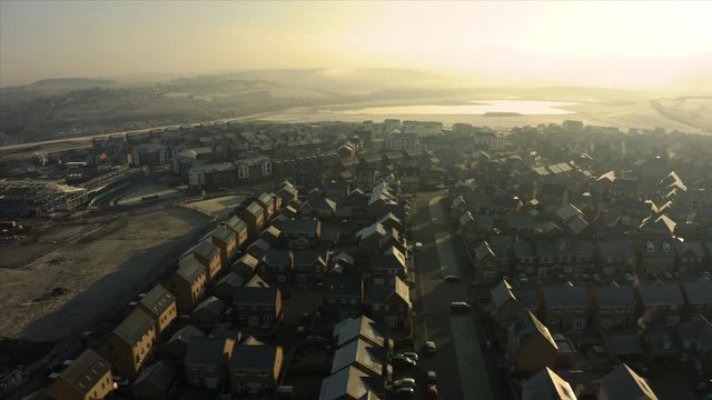 Aerial drone panning down street of new homes built on the Waverley residential estate in Rotherham, South Yorkshire druing a golden sunrise