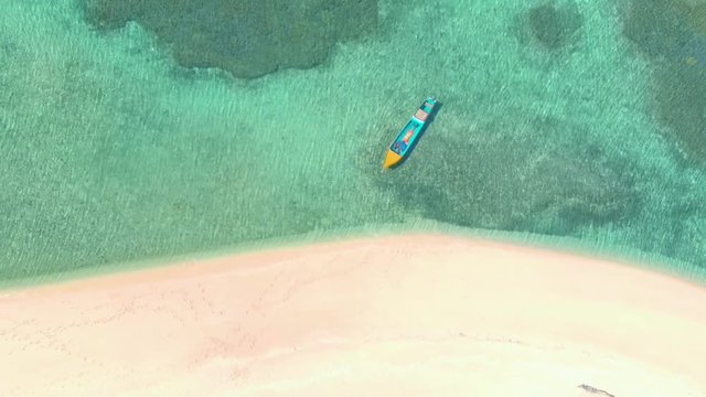 4K Tropical landscape of white sandy beach and coral reefs. Small boat surrounded by azure water and coral reefs in the white coast of Pink island in Balabac, Philippines	