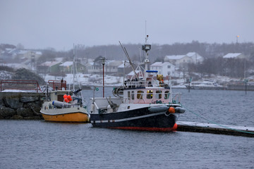 Fototapeta premium Boats at quay and snow in the air, Brønnøysund harborm in Nordland county