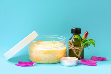 Dark bottle with black cap on light blue background with pink dog rose bud, petals and sea salt in jar with rose extract. Anti-ageing ingredient in cosmetics, source of vitamin E