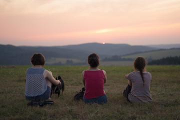 Naklejka na ściany i meble Three women watching sunset in Przemyskie Foothills, Poland
