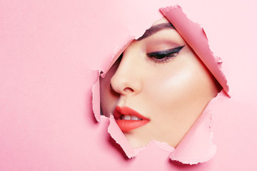 Beautiful face of a girl, professional makeup, arrows, long eyelashes, large lips. Pink background....