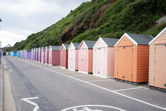 Colorful Beach huts, in orange, peach and pink colors, at the  boulevard in Bournemouth, Dorset, UK, England on a cloudy day in summer