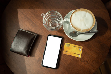 Credit cards and telephone are placed on a wooden table at the coffee shop.