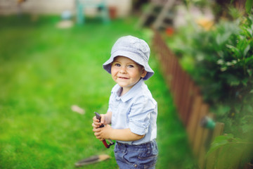 Toddler boy Toddler in a hat with tools backyard