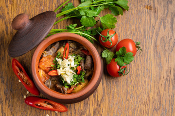 Pot of hungarian goulash on rustic wood background with chili peppers and laurel and copy space