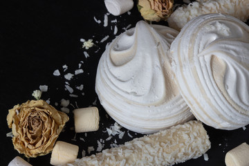airy white marshmallows on a black background top and side view. Delicious dessert, mashmeloe, coconut and pepper sticks. Cooking and sweets recipe