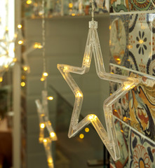 Christmas star-shaped LED garland hanging in a room near the fireplace. christmas tree in the background