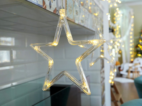 Christmas star-shaped LED garland hanging in a room near the fireplace. christmas tree in the background
