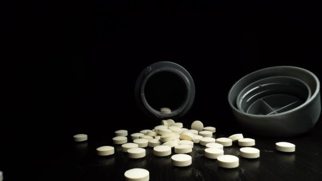 Macro shot of tablets or pills on a table zooming out of a bottle.