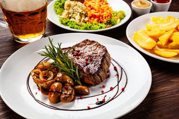 Grilled sirloin steak and vegetables on wooden background