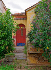 weathered vintage house entrance red arched door and garden