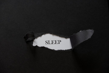 Word SLEEP printed on a white background with black torn paper.