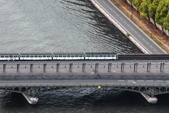 A white and blue metro train rides on a bridge over the Senna River in Paris, France.