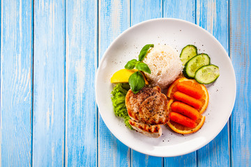 Roast steak with white rice and vegetables on wooden background