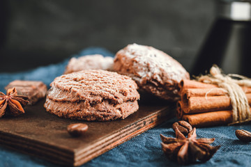 Homemade bakery, chocolate cookies with powdered sugar, cinnamon sticks, star anise on blue napkin, dark background