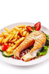 Barbecued salmon, french fries and vegetables on white background