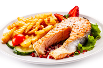 Barbecued salmon, french fries and vegetables on white background