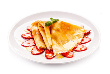 Tasty crepes with strawberries on white background