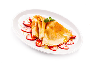 Tasty crepes with strawberries on white background