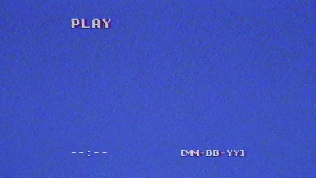 An old VHS tape capture, analog signal with an intentional distortion effect. Blue background, small text with a missing date, a play message, bad artifacts. Long-lasting clip.