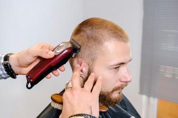 Barber shaves the client's head with a trimmer.