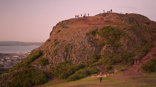 People climbing on top of the Holyrood park Arthur's seat mountain for a sunset time to take a view over the city of Edinburgh in Scotland