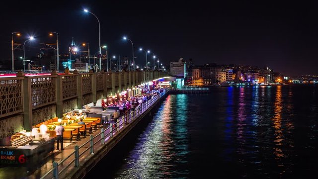 Restaurants on Galata bridge over the Golden Horn, Istanbul, Turkey time lapse at night