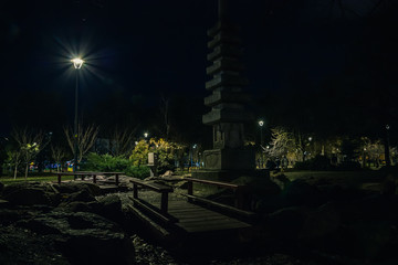 Night park with Japanese architecture. Two little bridges and lanterns shine