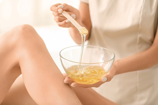 Young woman undergoing epilation of legs in beauty salon