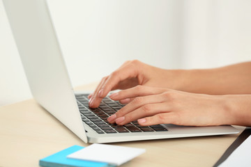 Fototapeta na wymiar Beautiful young businesswoman working on laptop in office, closeup