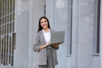 Beautiful young businesswoman with laptop outdoors