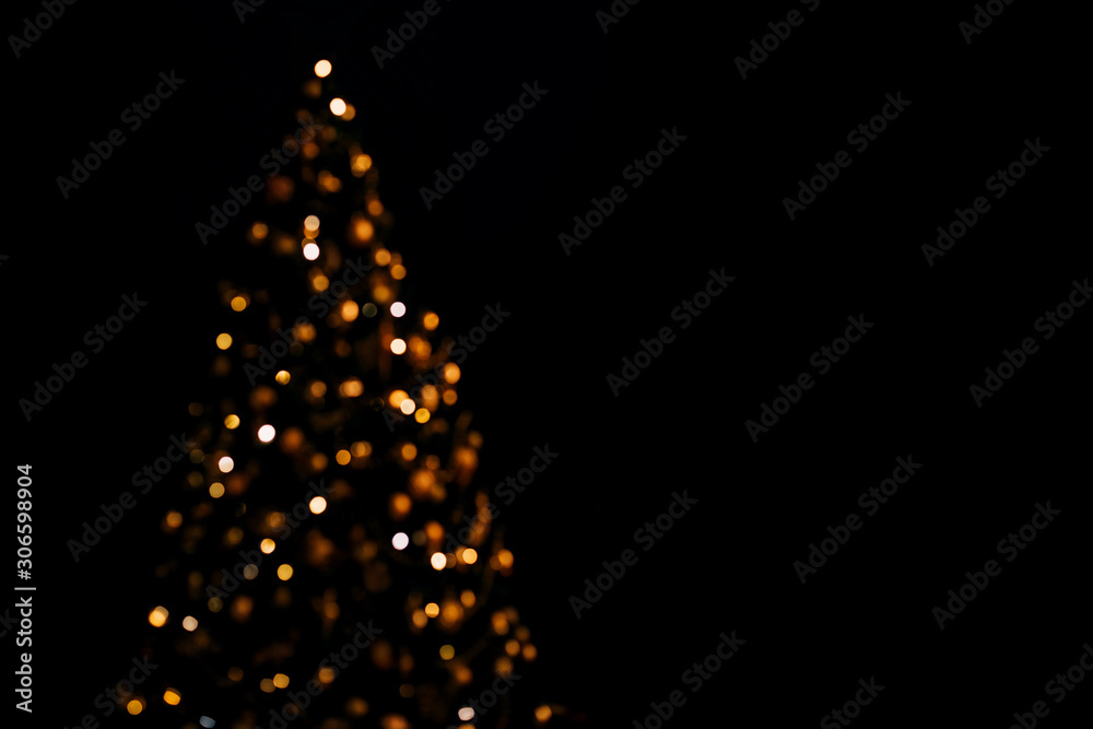 Wall mural lights of christmas tree blurred bokeh on dark background with copy space.