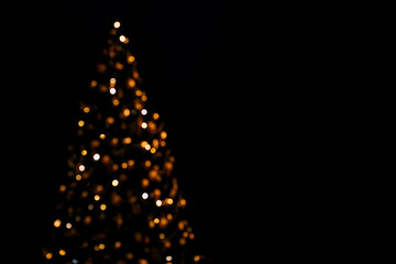 Lights of christmas tree blurred bokeh on dark background with copy space. - obrazy, fototapety, plakaty