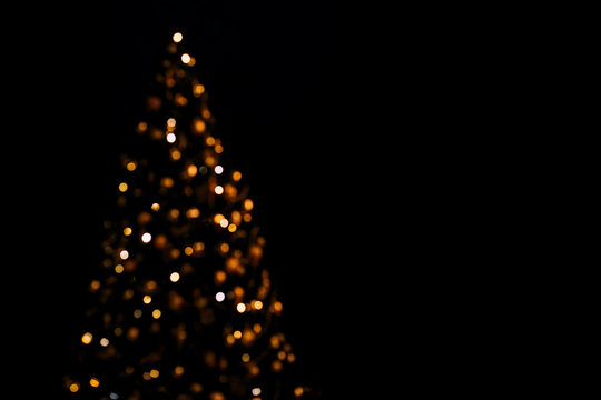 Lights of christmas tree blurred bokeh on dark background with copy space.