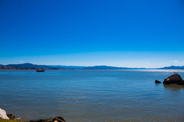 Tropical blue sea in sunny day and boat in the blue mountains in Florianópolis