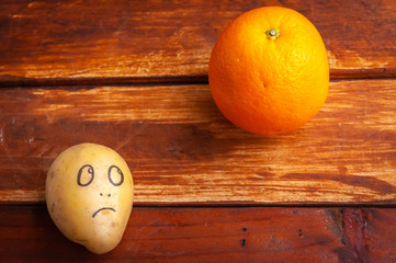 potato with an emotional face looks at citruses.