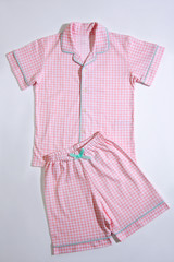 Baby pajamas. Sleeping outfit for baby girl. Pajamas in pink and white colors, square pattern. On white background