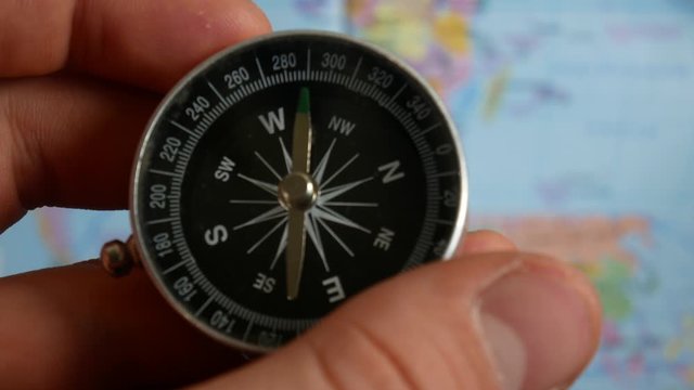 Male hands open a map and use a compass. Checking direction with a compass in hands. Close-up shot of a spinning vintage compass. - Powered by Adobe