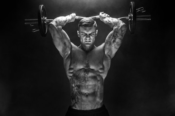 Portrait of muscular man lifting dumbbell. Studio shot. Exercise for triceps. Motivation.